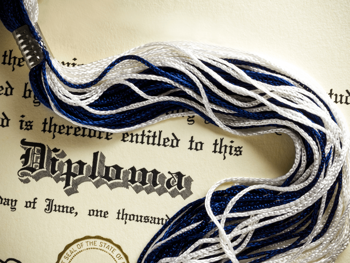 diploma with gold state seal under a blue and white graduation cap tassel